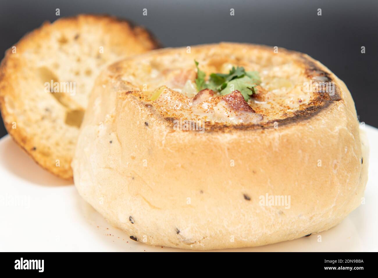 Bowl of hearty clam chowder contained in an oven baked bread bowl. Stock Photo