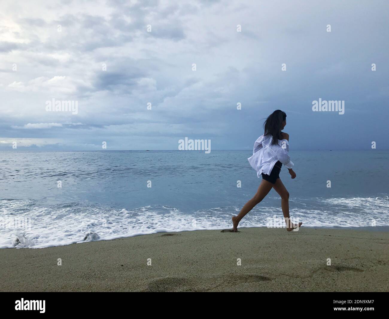 Full Length Of Woman Walking At Beach Against Sky Stock Photo