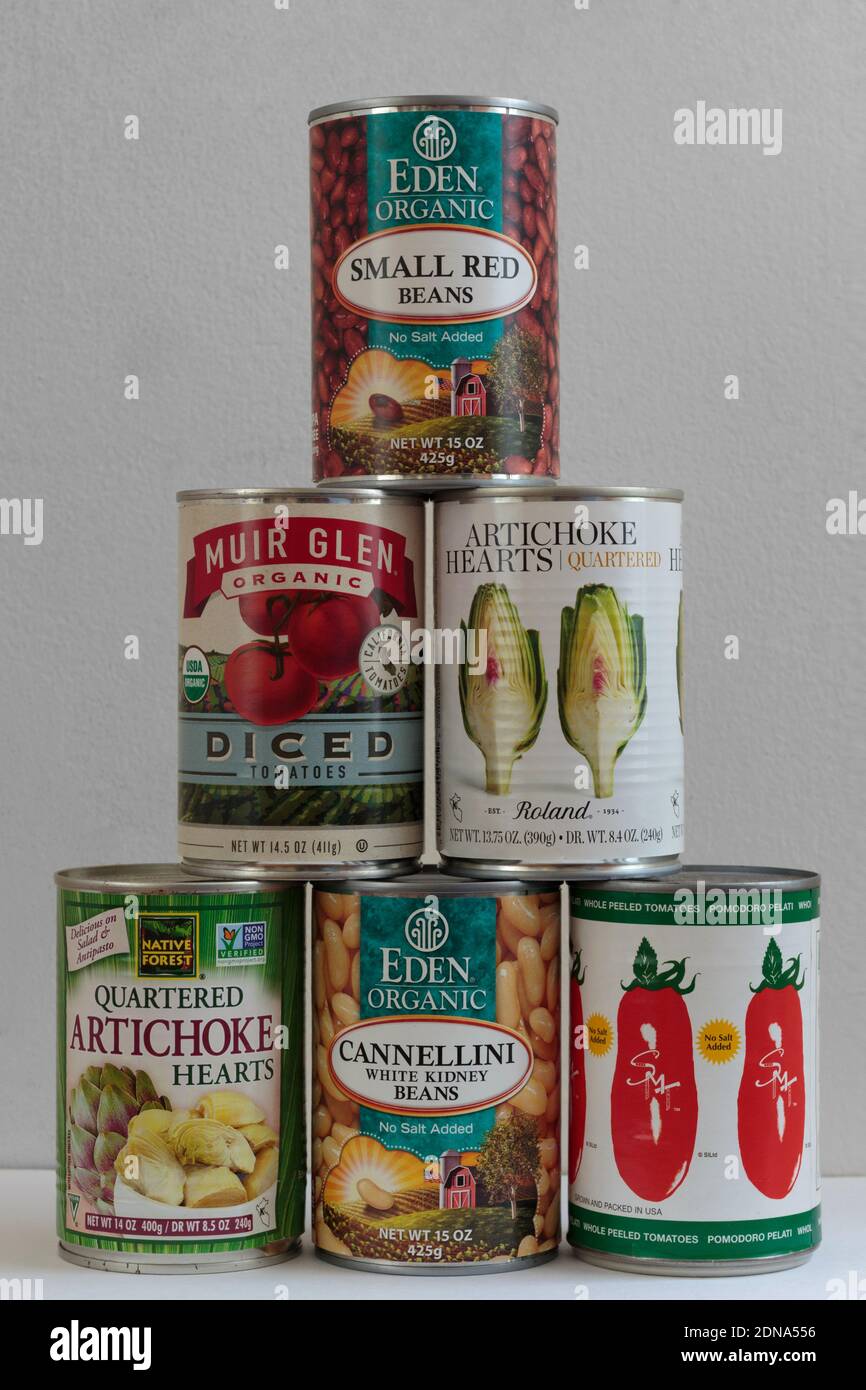 illustrative editorial of cans or tins of food stacked in a pyramid on a white background, small red beans, cannellini beans, tomatoes, artichokes Stock Photo