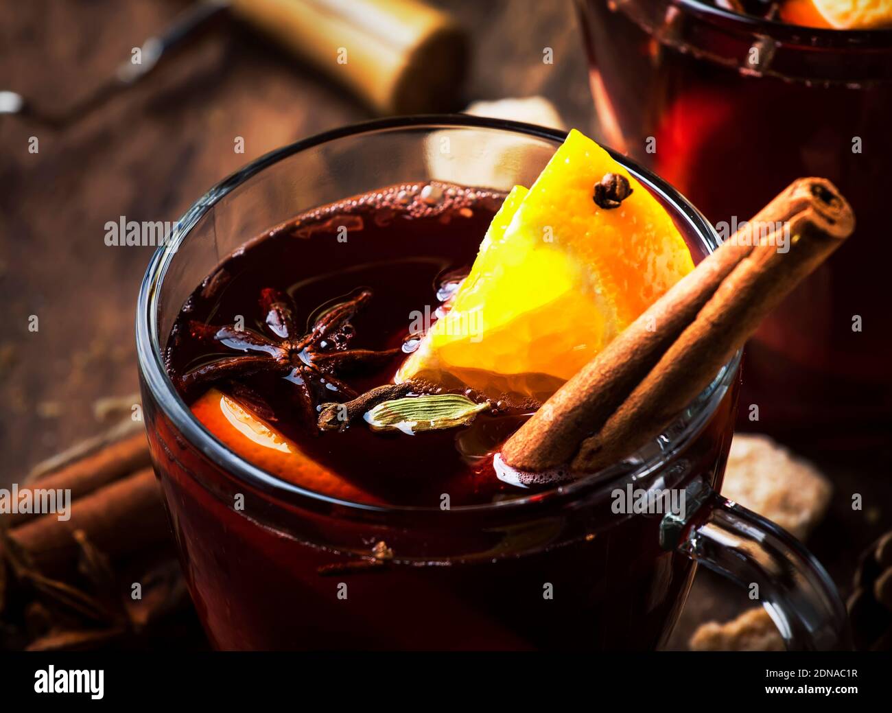 Xmas hot mulled red wine with spices and fruits on wooden rustic table. Traditional Christmas hot drink in festive table setting Stock Photo