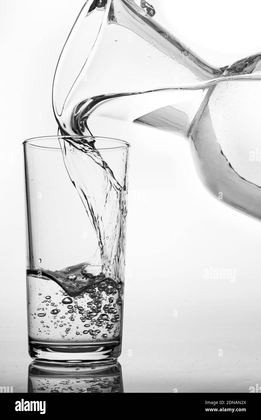 https://c8.alamy.com/comp/2DNAN2X/pouring-water-from-a-jug-into-a-glass-containers-for-feeding-water-in-the-household-light-background-2DNAN2X.jpg
