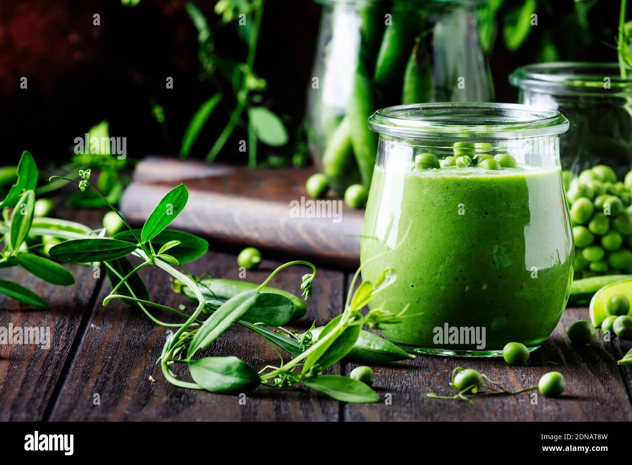 Cream soup from green peas in glass jar on vintage wooden background, selective focus Stock Photo
