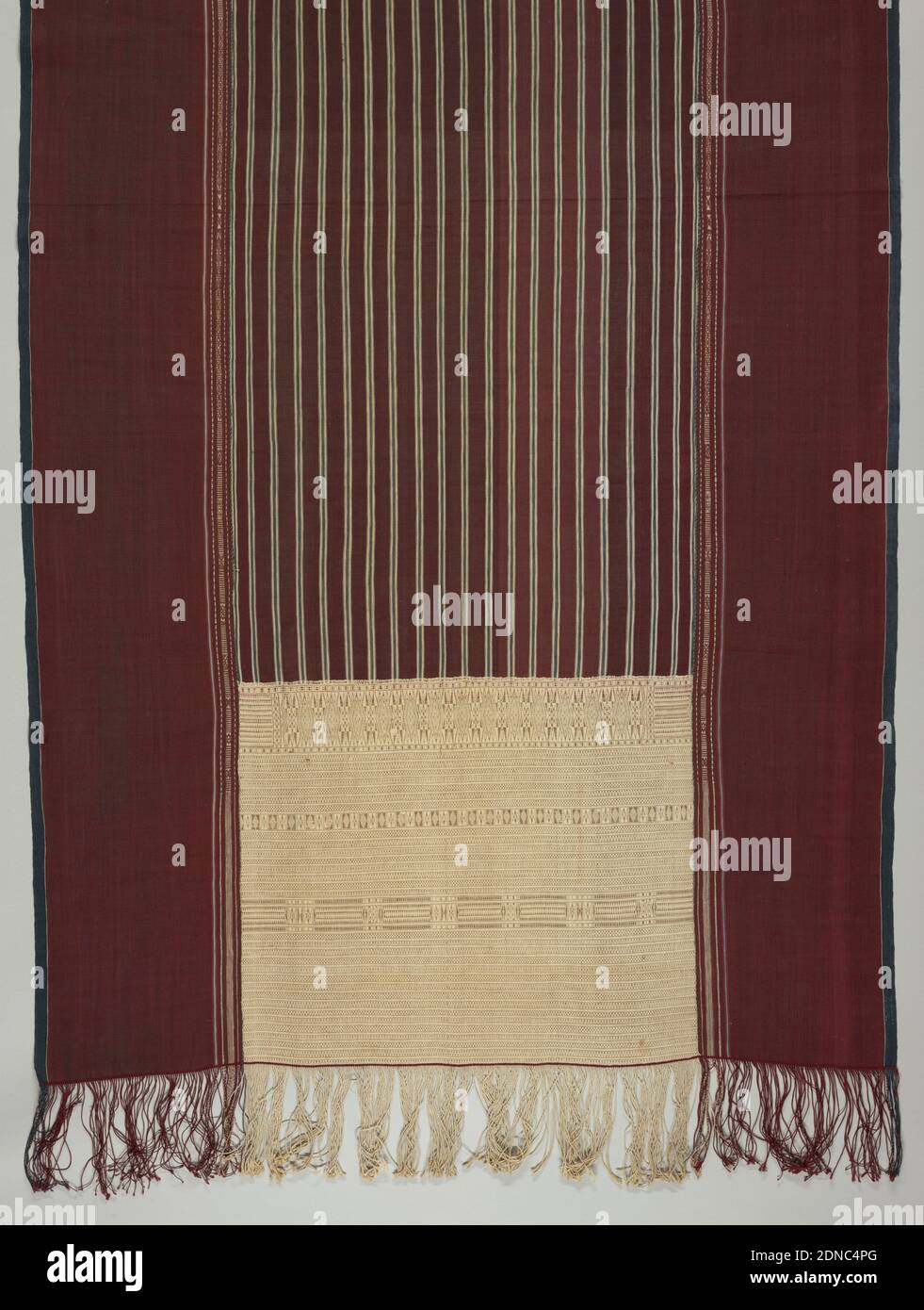 Ulos ragidup (ceremonial shoulder cloth), Medium: cotton Technique: tied resist patterning in warp or weft (ikat) on plain weave, with supplementary weft patterning, Ulos ragidup, 'the cloth with the pattern of life', is a large ceremonial selendang (shoulder cloth) which is wrapped around the groom's mother by the bride's father at a wedding. Center area in dark maroon with vertical stripes of light blue and a bright red-brown. Ornamented on either end with intricate insets of cream color with horizontal bands of design, by making use of one additional warp. Wide borders in dark red Stock Photo