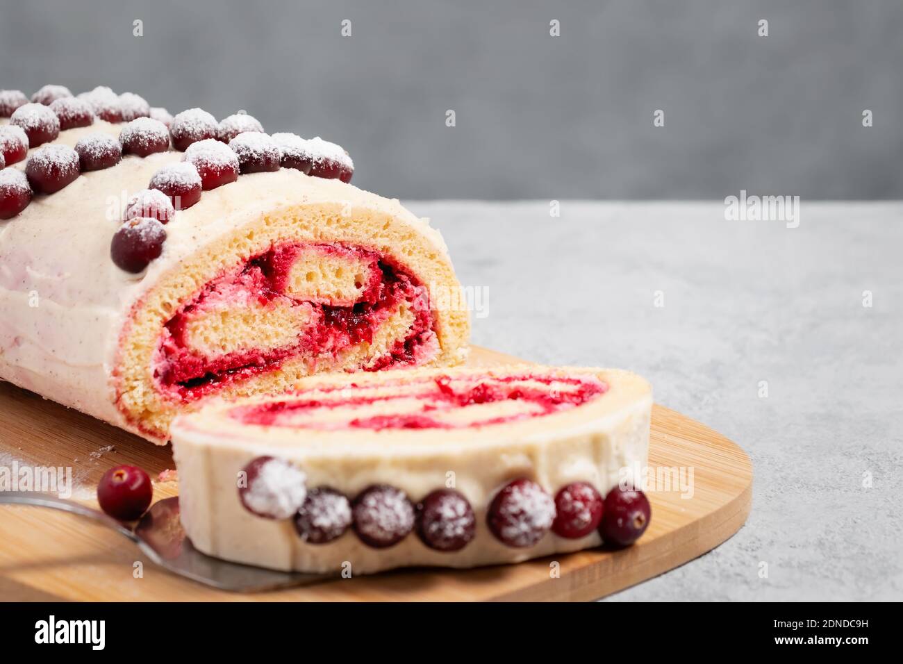 Homemade biscuit sweet roll with cranberries and cream on gray table, copy space Stock Photo