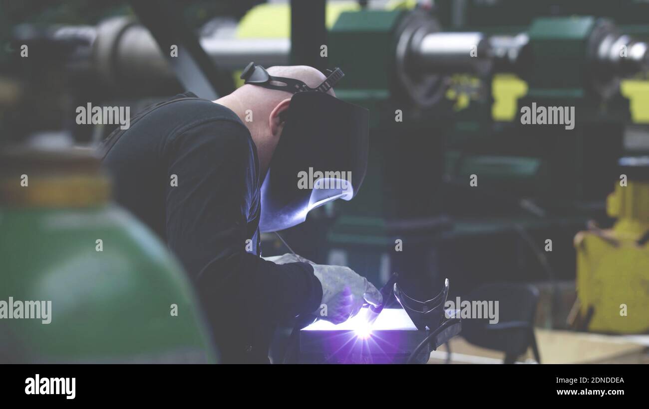 professional weld worker while using TIG Welding, wearing safety protective mask in selective focus view. Gas tungsten arc welding GTAW torch welder b Stock Photo