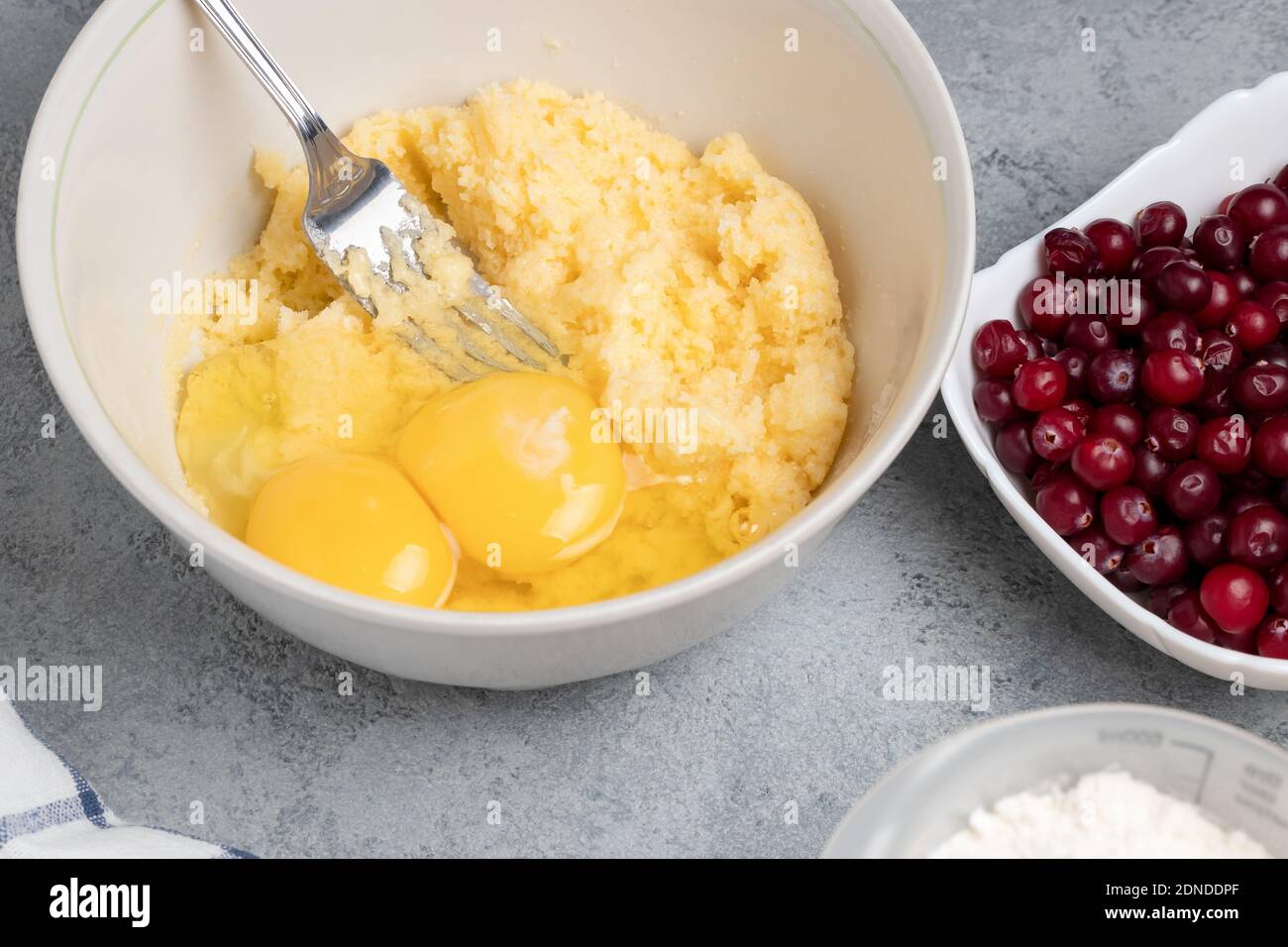 Making a dough for a sweet cranberry pie. Adding eggs Stock Photo