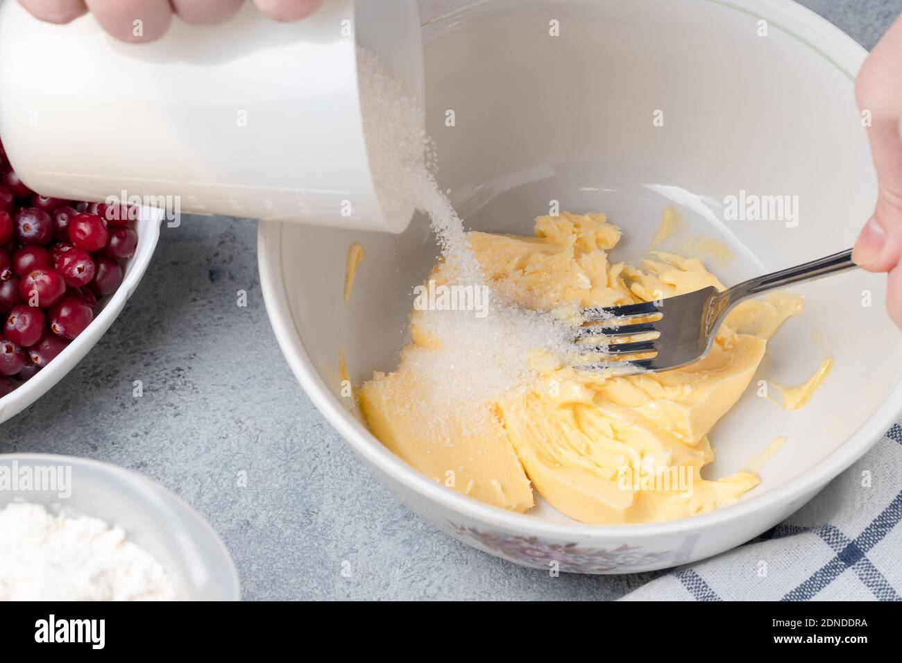 Making a dough for a sweet cranberry pie. Pouring sugar into butter Stock Photo