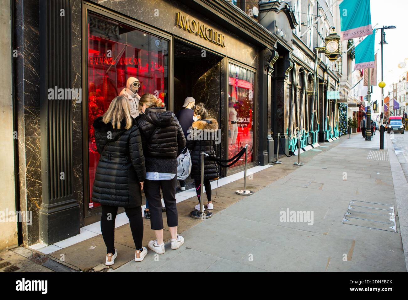 People queue outside Moncler shop in Old Bond Street.Non-essential shops  are still allowed to stay open in Tier 3 areas. Many retailers will still  be open for all Christmas shopping needs Stock