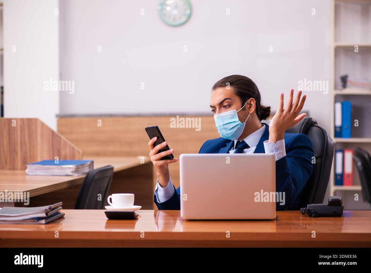 Young employee working in the office wearing mask Stock Photo - Alamy