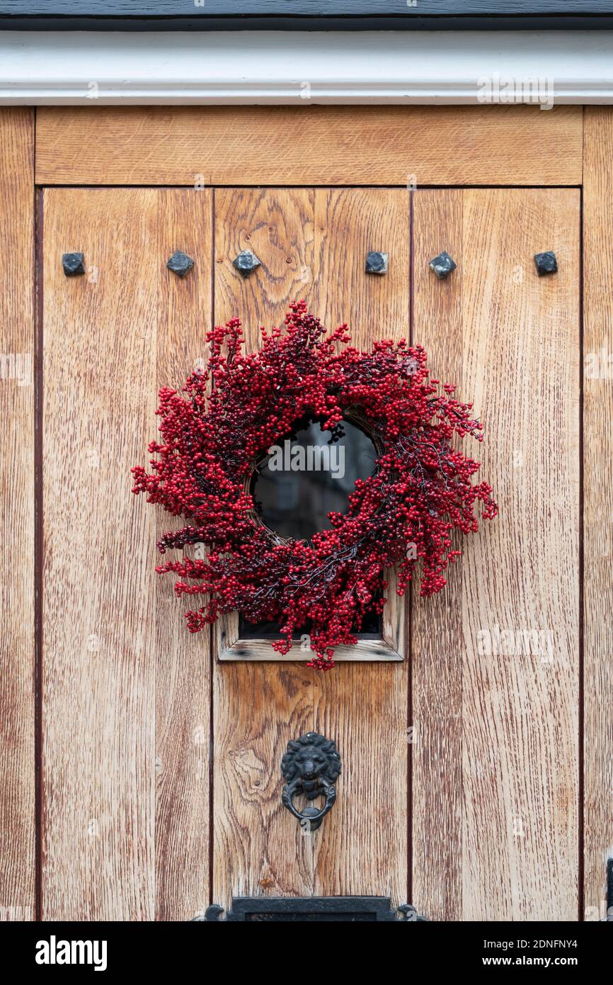 Red berry christmas wreath on a town house wooden door. Woodstock, Oxfordshire, England Stock Photo
