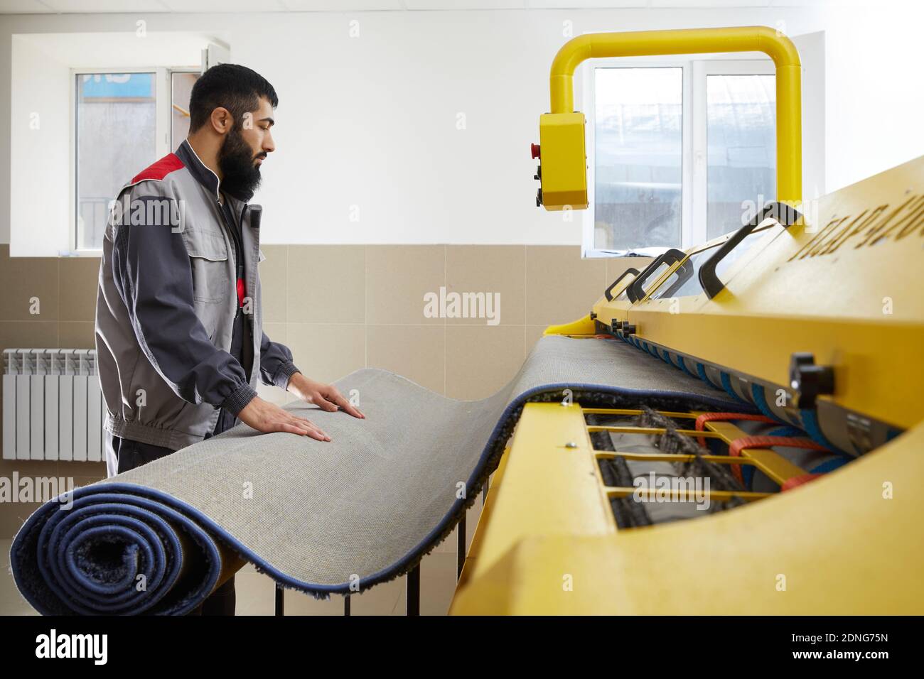 Man operating carpet automatic washing machine in professional laundry service Stock Photo