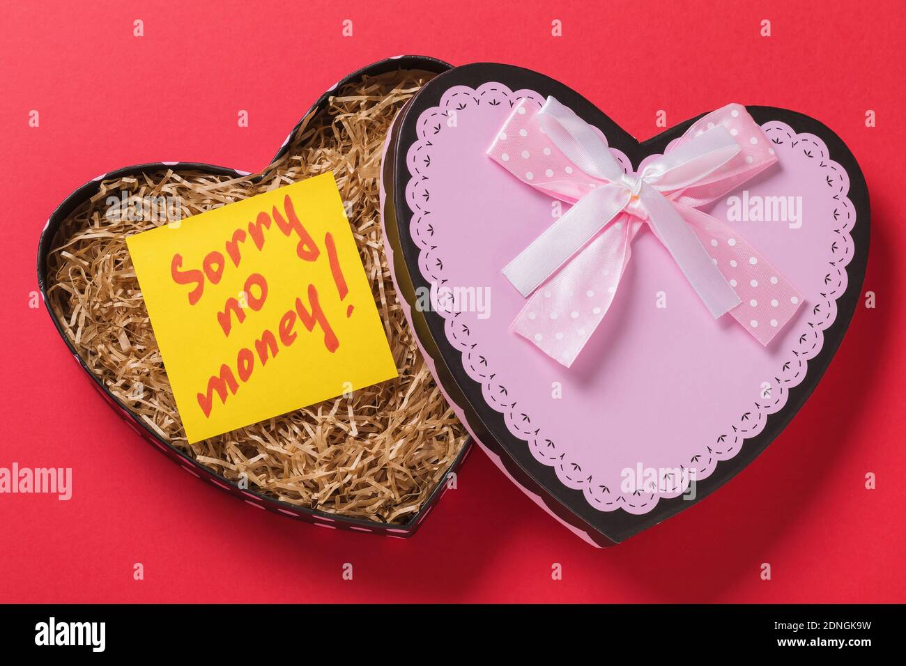 Open gift box with a note inside on a red background. The concept of no money for gifts. Stock Photo