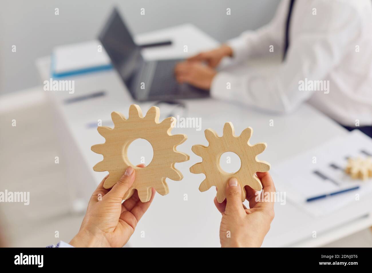 Company manager holding two cogwheels as metaphor for effective business management Stock Photo