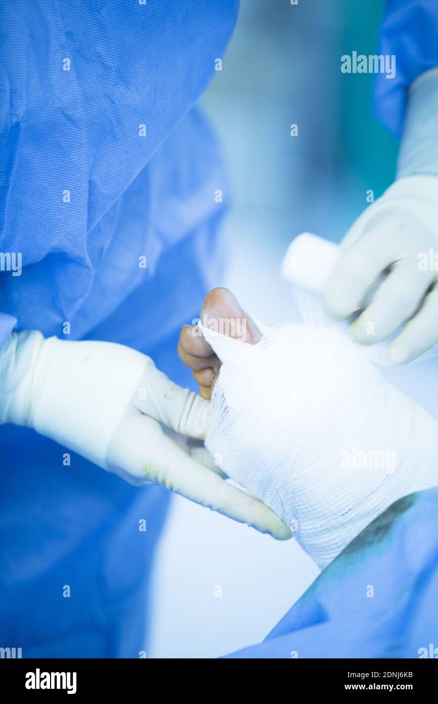 Midsection Of Surgeon Wrapping Bandage On Patient Wound In Operating