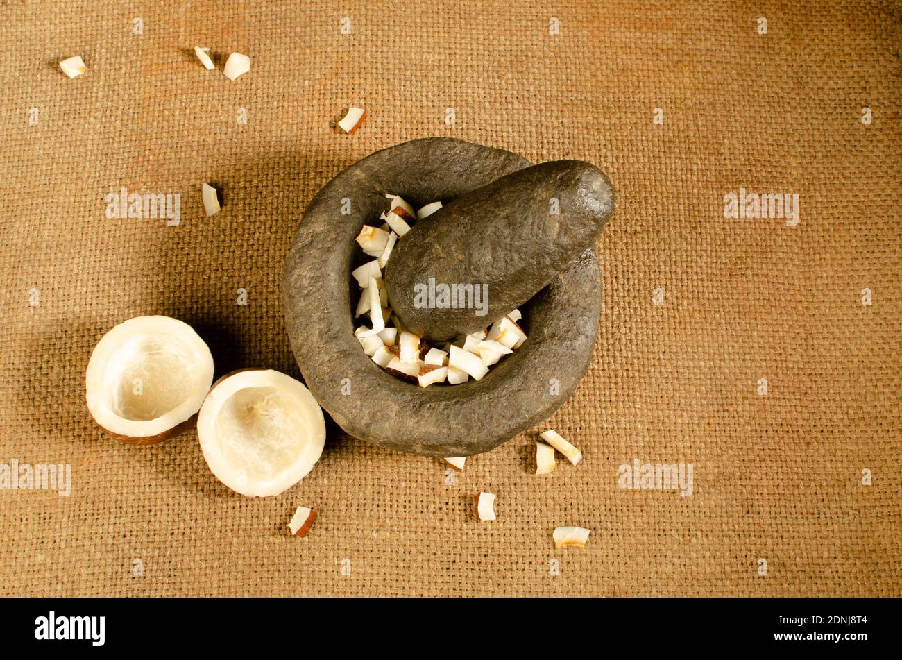 Indian stone Mortar and Pestle Set with  dried coconut pieces in mortar. Studio Shot Stock Photo