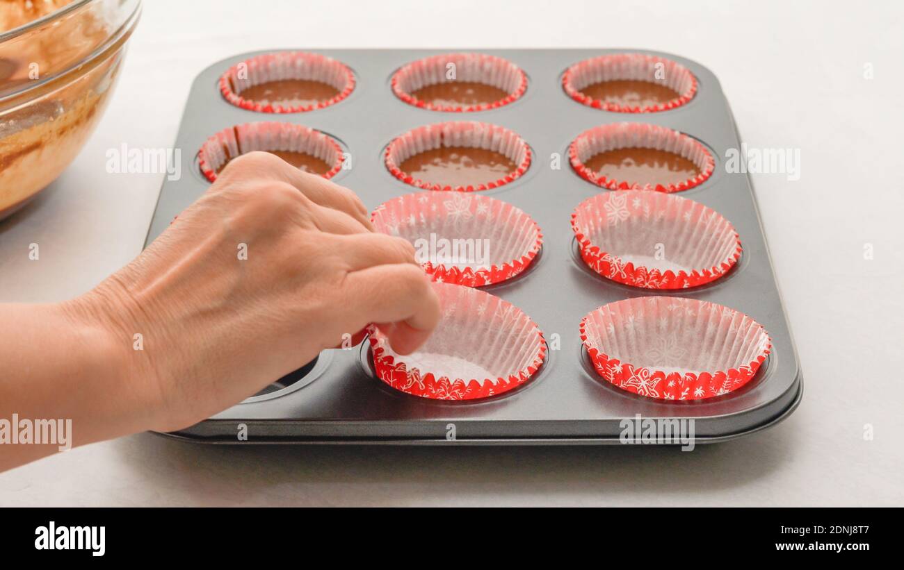 Muffin pan with paper cupcake liners close up on kitchen table woman hands Stock Photo Alamy