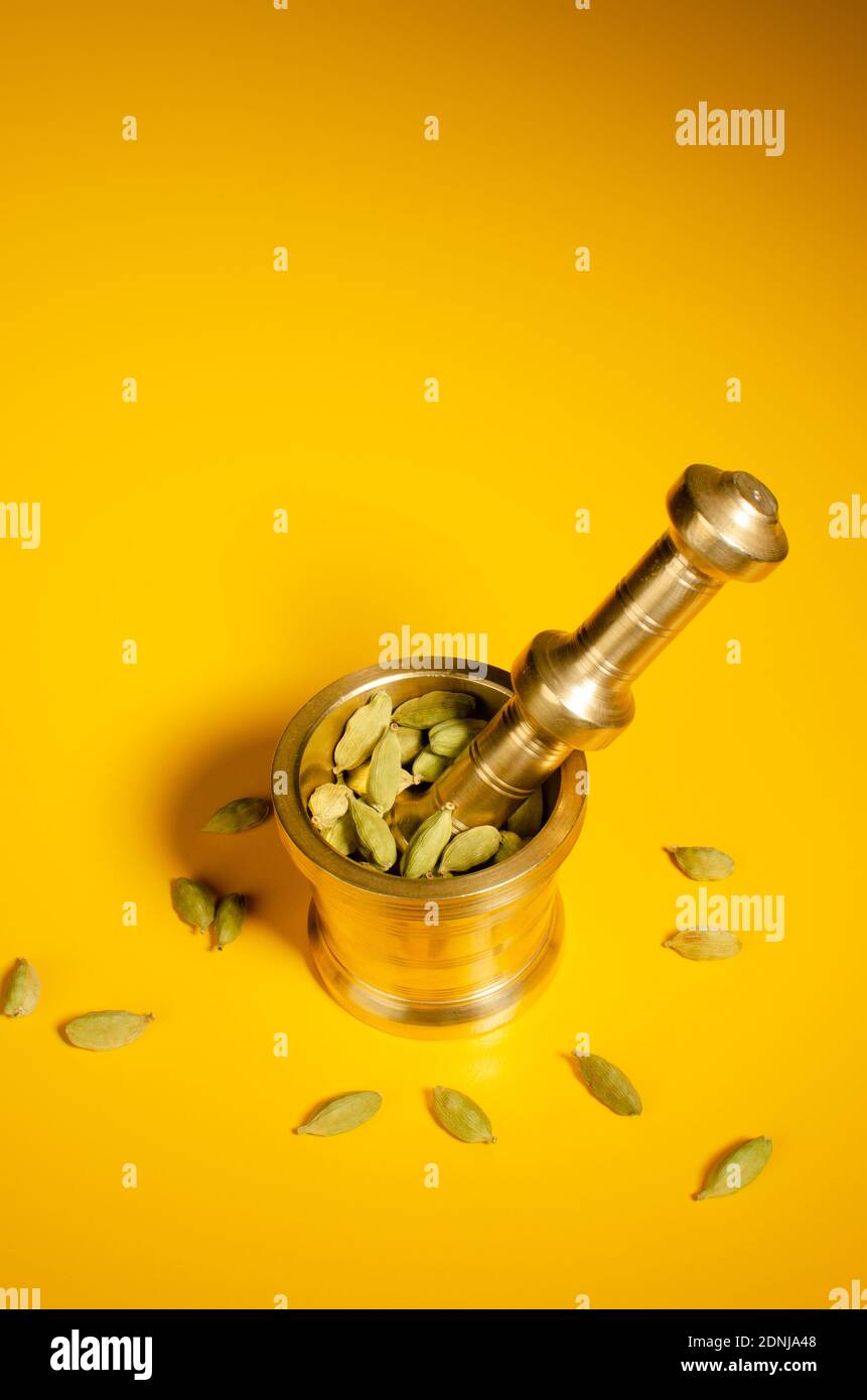 Indian Brass Mortar and Pestle Set with Green Cardamom pods in Mortar.  Top Angle View. Studio Shot Stock Photo