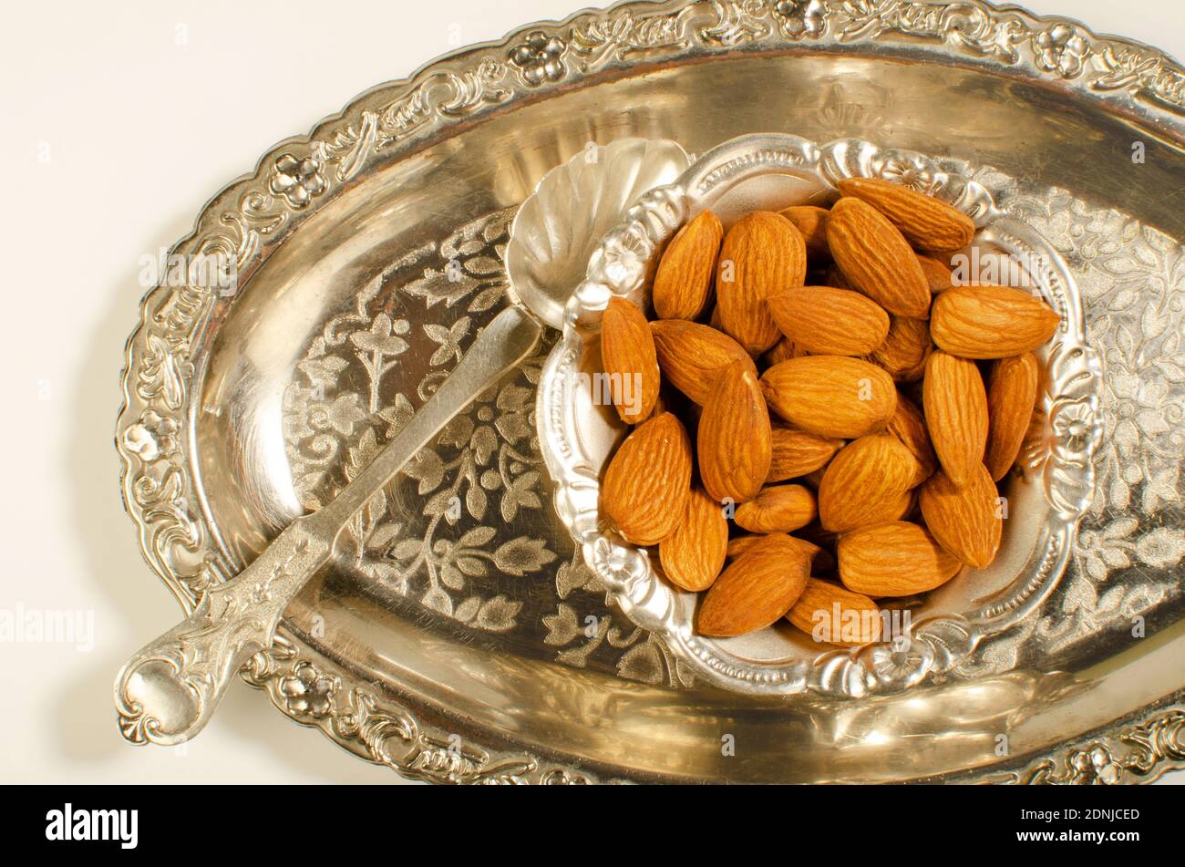 Almonds or Badam dried Fruit presented in a decorative Silver Bowl. Studio Shot Stock Photo