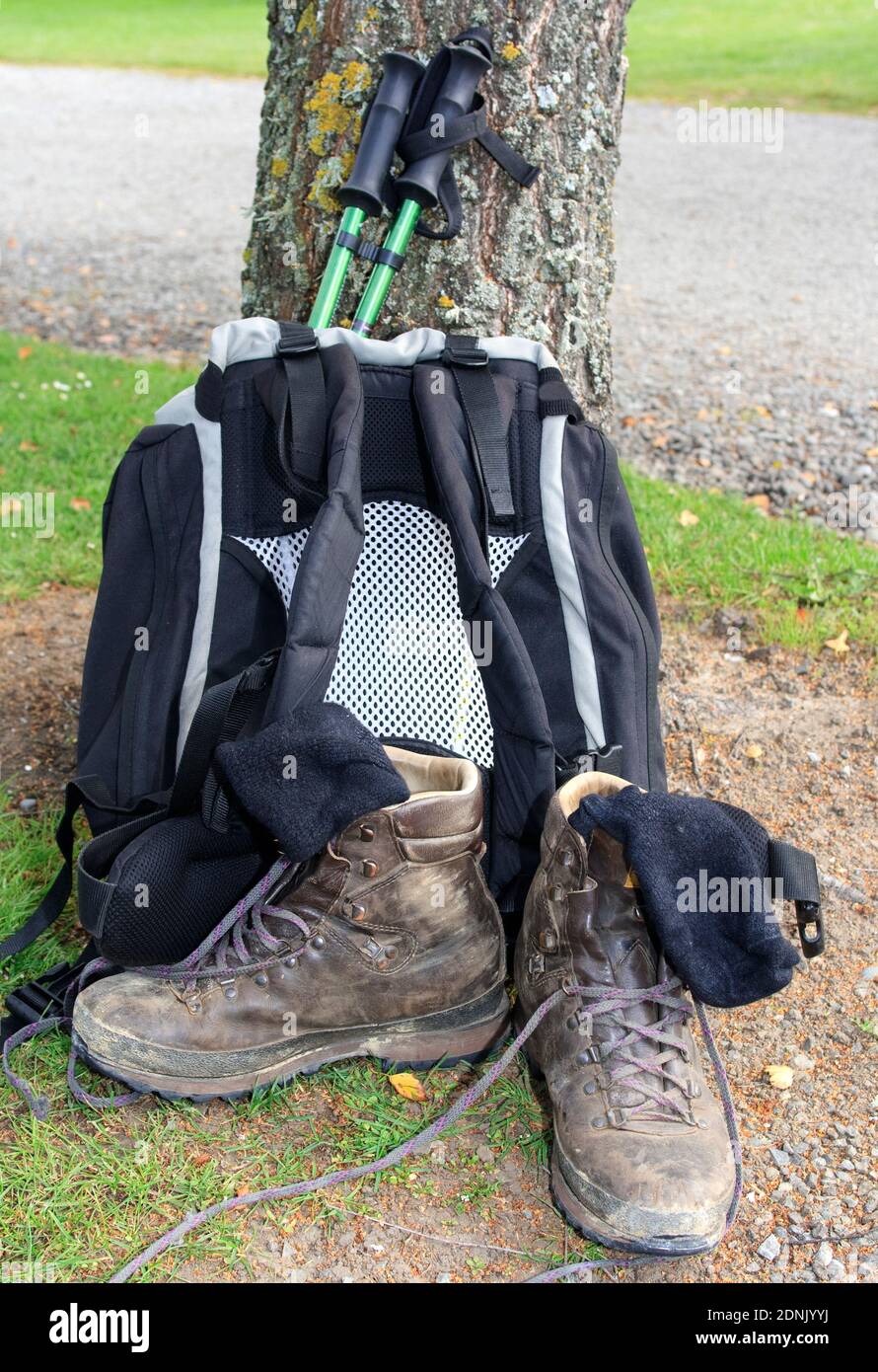 Backpack leaning against tree with hiking poles, hiking boots and socks ...