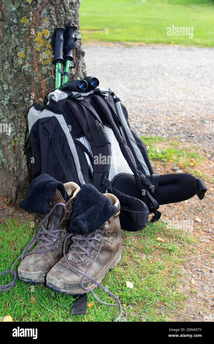 Backpack leaning against tree with hiking poles, hiking boots and socks ...