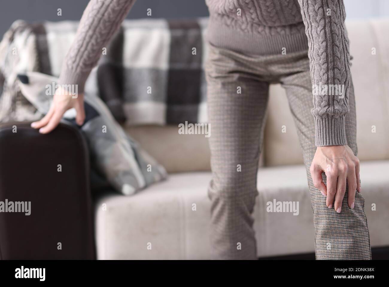 Man getting up from couch and holding on to sore knee closeup Stock Photo