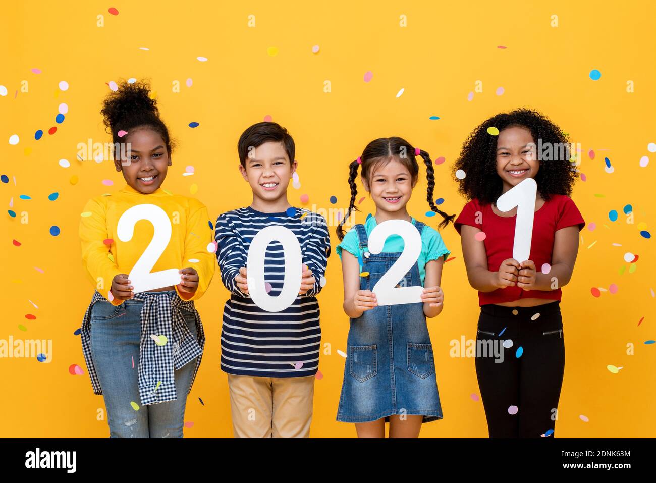 Cute smiling diverse kids showing numbers 2021 celebrating new year isolated on yellow background Stock Photo