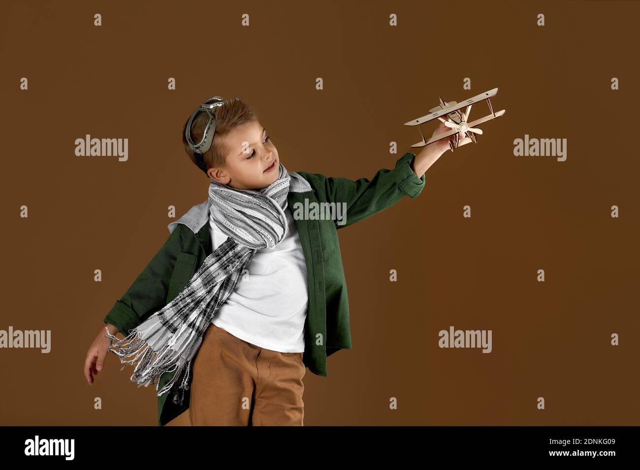 happy child boy playing with wooden toy airplane on studio background ...
