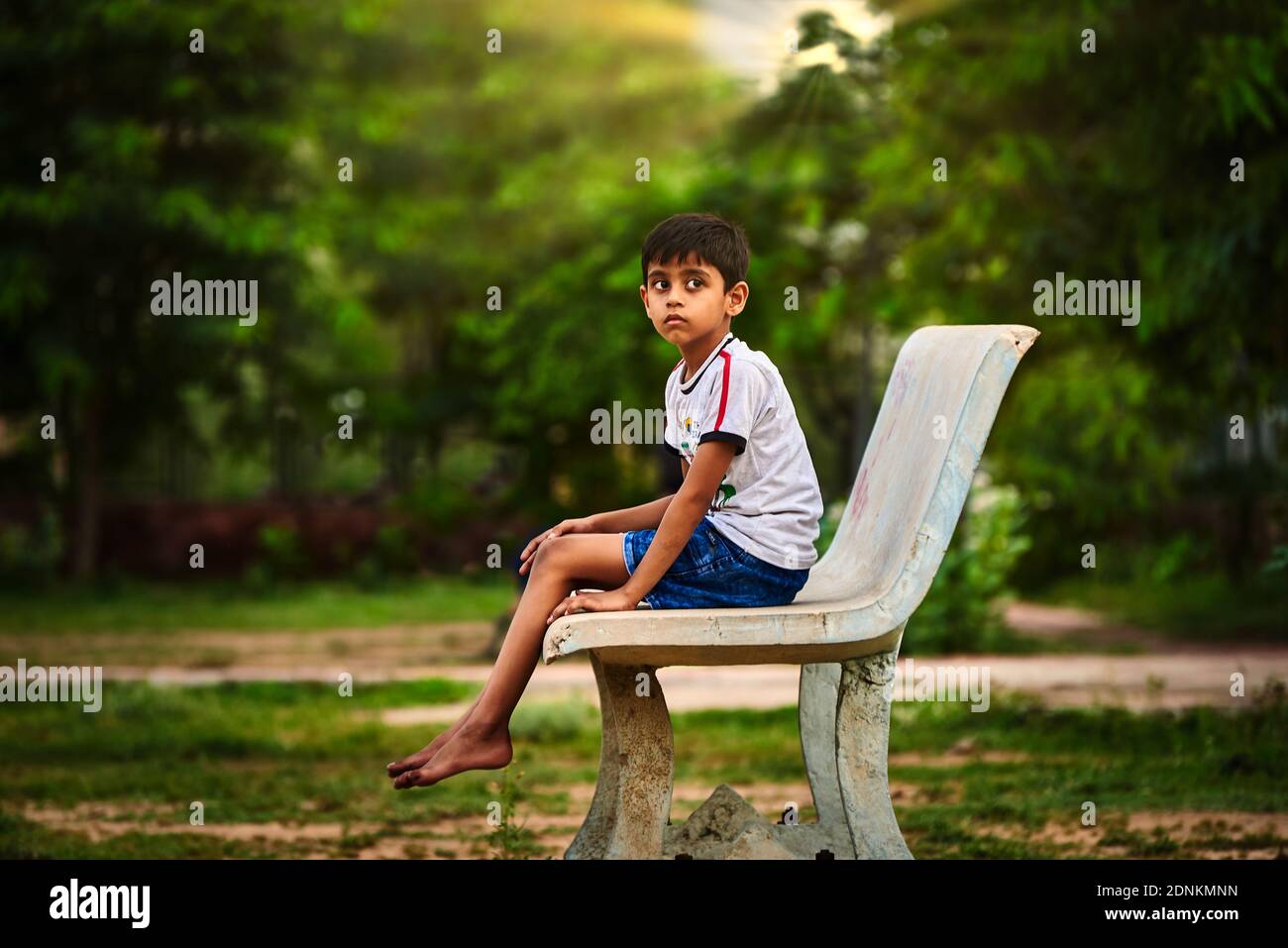 Side View Of Thoughtful Boy Sitting On Bench At Park Stock Photo - Alamy