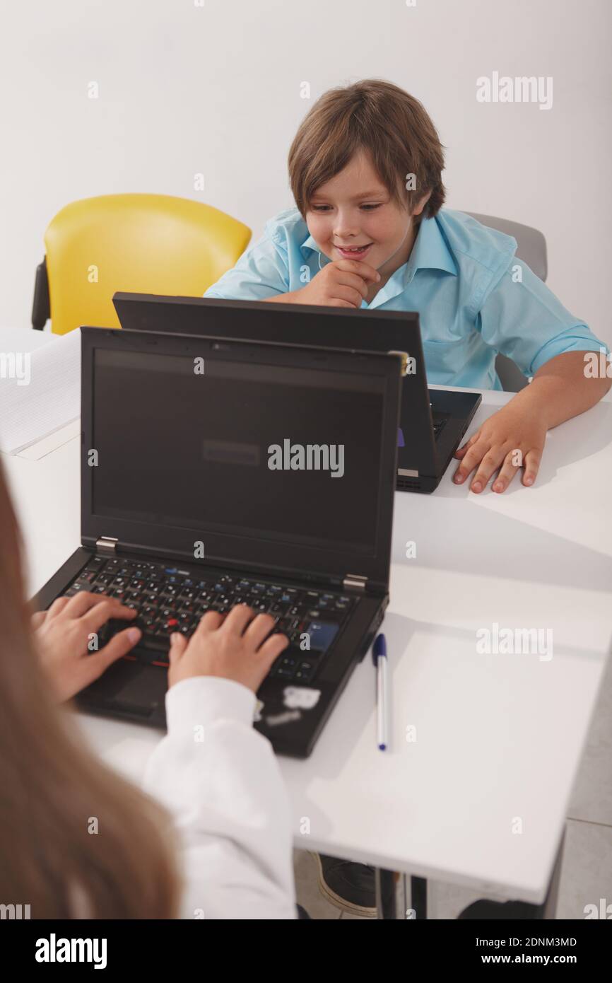 Vertical shot of a cute funny boy studying on his computer at class Stock Photo