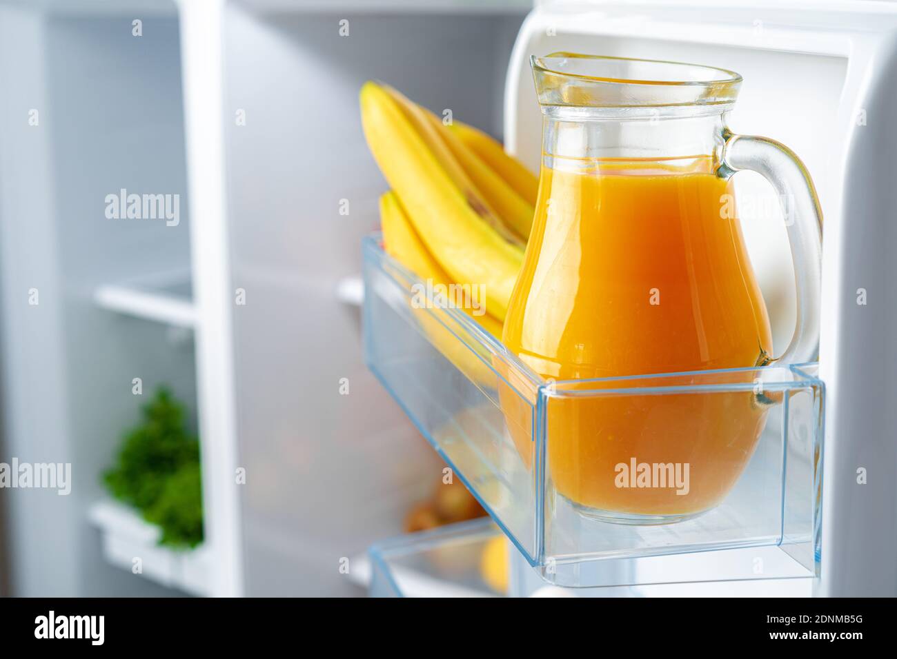https://c8.alamy.com/comp/2DNMB5G/glass-pitcher-of-orange-juice-and-fruits-on-fridge-shelf-2DNMB5G.jpg