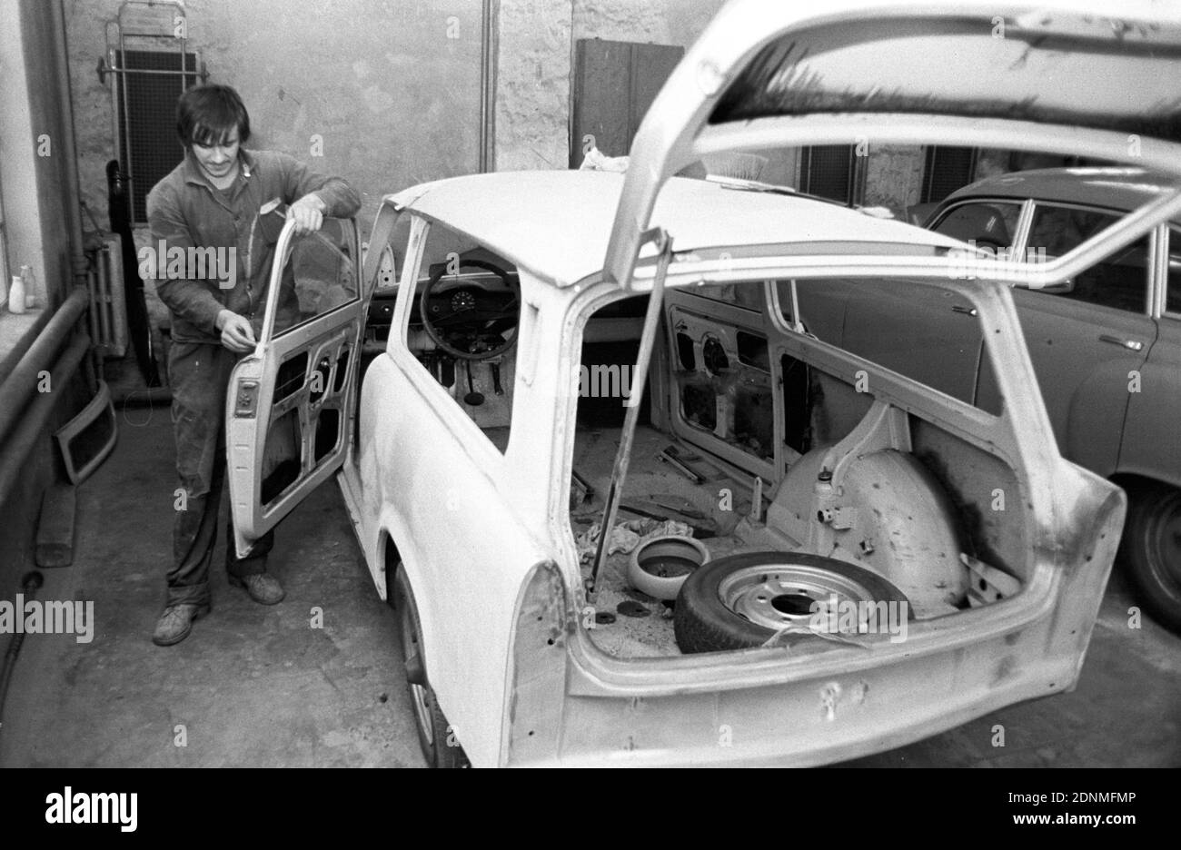 15 October 1981, Saxony, Eilenburg: In a private paint shop in the early 1980s in Eilenburg, a painter is carrying out painting work on a Trabant station wagon and a Skoda without protective clothing. Exact date of recording not known. Photo: Volkmar Heinz/dpa-Zentralbild/ZB Stock Photo