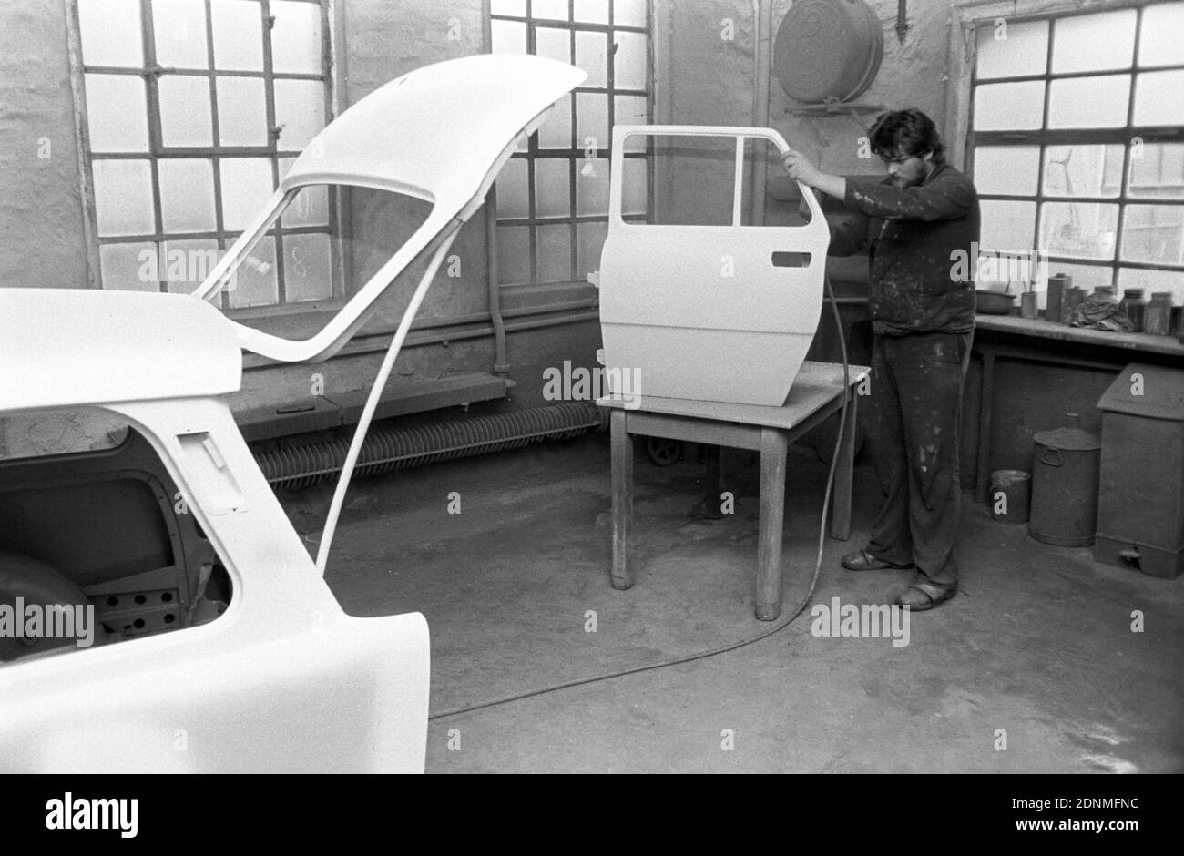 15 October 1981, Saxony, Eilenburg: In a private paint shop in the early 1980s in Eilenburg, a painter is carrying out painting work on a Trabant station wagon and a Skoda without protective clothing. Exact date of recording not known. Photo: Volkmar Heinz/dpa-Zentralbild/ZB Stock Photo