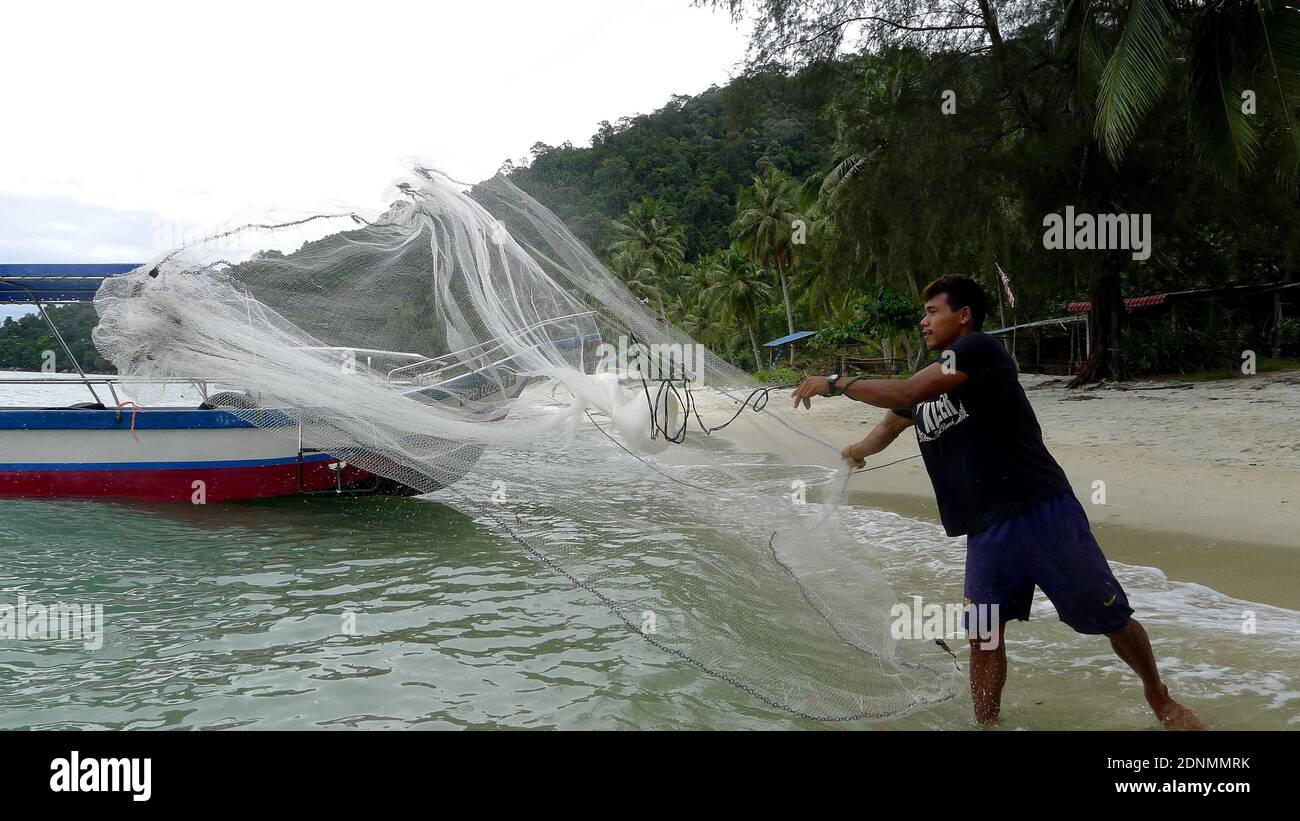 Fisher man throwing fishing net for catching fish for food Stock