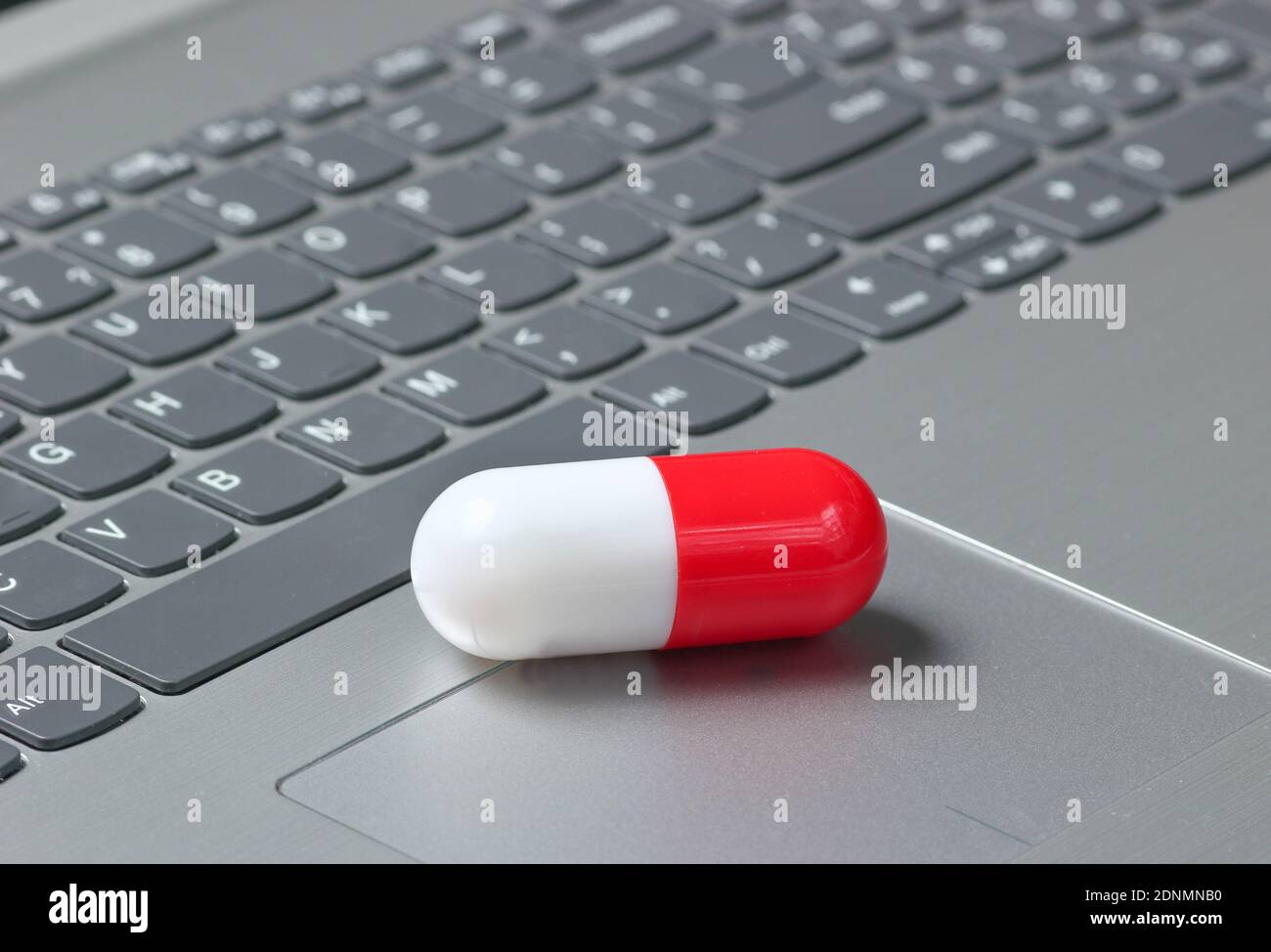 White red medical capsule pill closeup on laptop keyboard Stock Photo