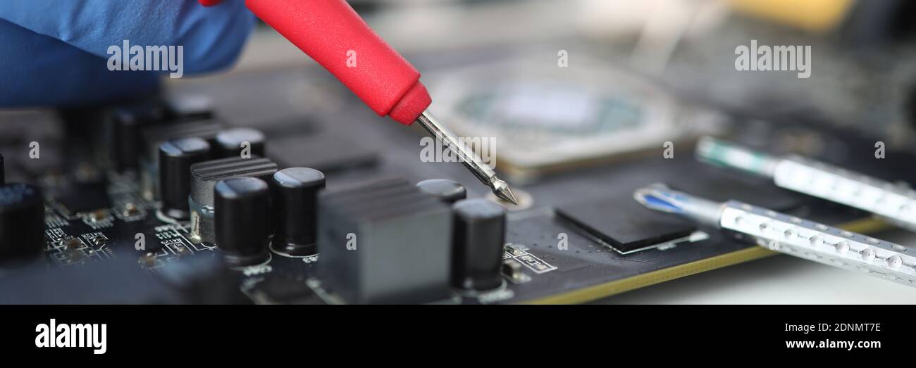 Gloved master holds probe over microcircuit closeup Stock Photo