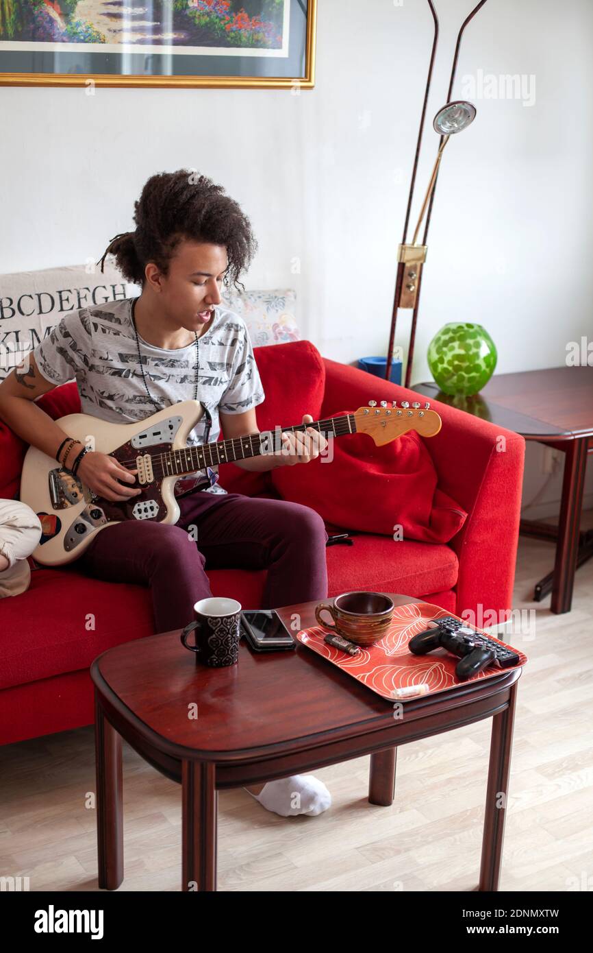 Young man playing guitar on sofa Stock Photo