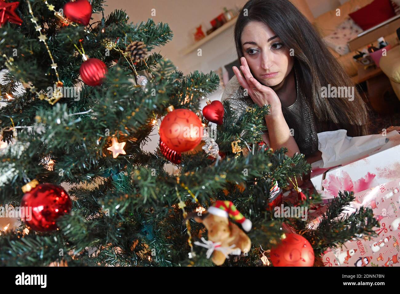 Munich, Deutschland. 17th Dec, 2020. Topic picture Lonely Weihafterten 2020 in the coronavirus pandemic. A young woman with face mask, mask sits alone behind her Weihaftertsbaum on Christmas Eve and is sad, wipes tears from her eyes, weeps, weep, pandemic, lockdown, shutdown, incidence value. MODEL RELEASED! | usage worldwide Credit: dpa/Alamy Live News Stock Photo