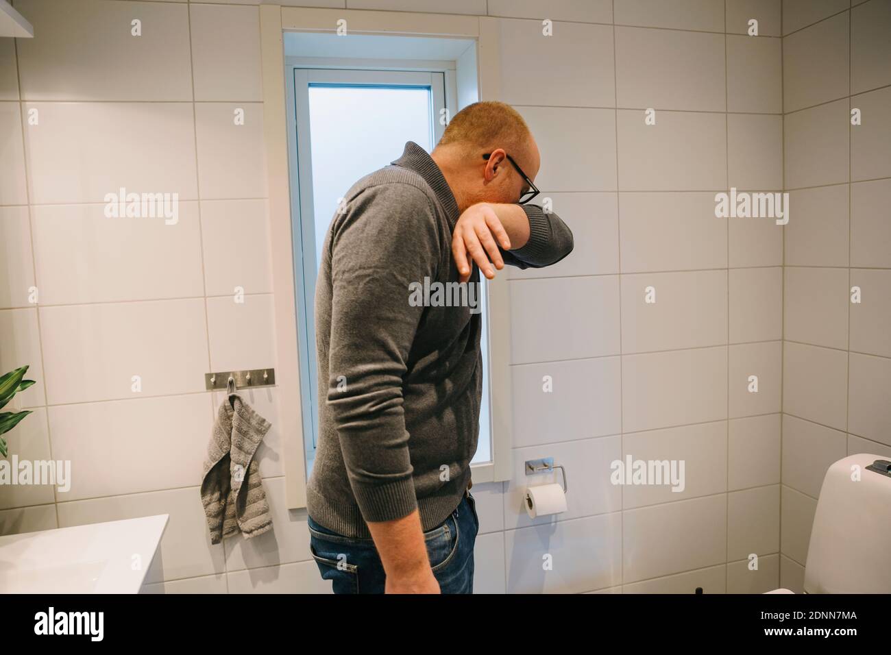 Man coughing in arm Stock Photo