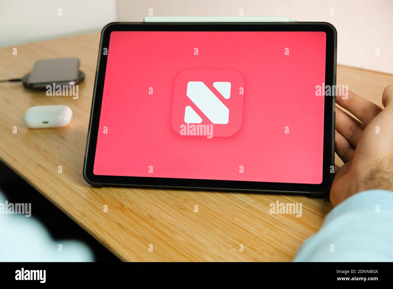 Apple News plus logo on the screen of iPad tablet with smart phone iPhone  charging on the wireless charger and airpods in the case on the background  Stock Photo - Alamy
