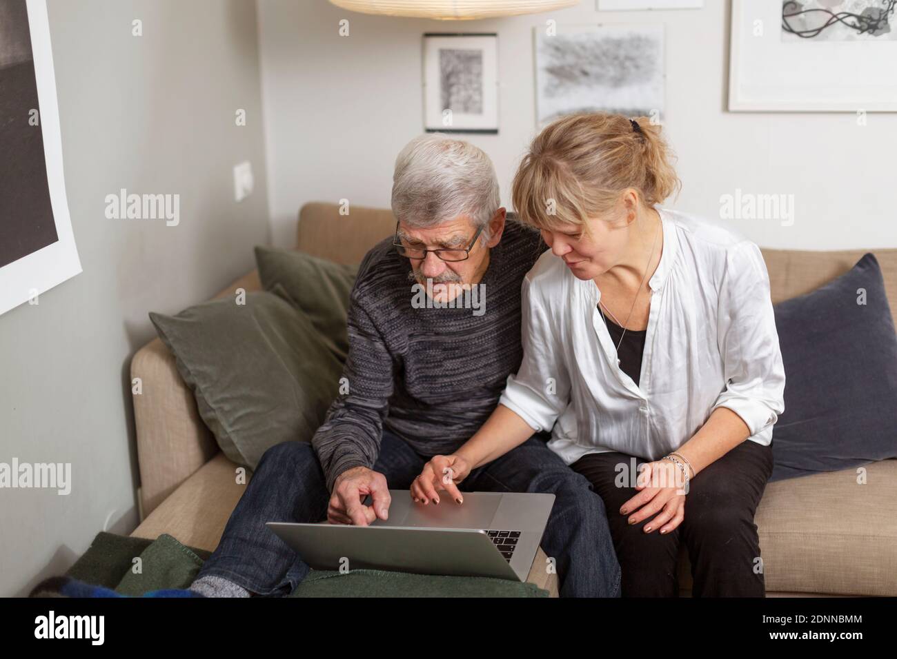 Couple using laptop on sofa Stock Photo