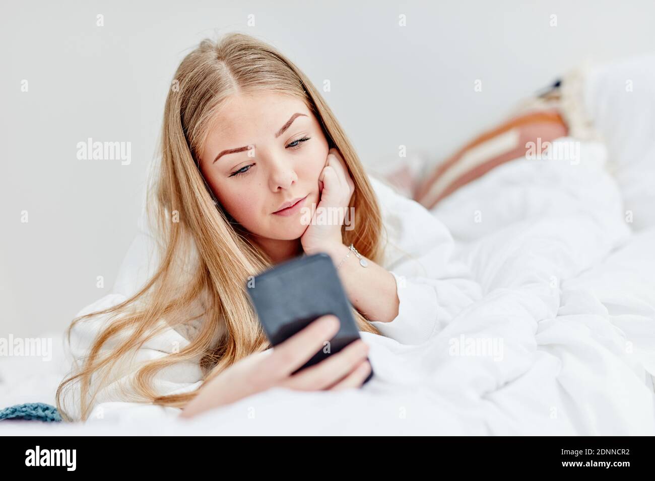 Woman in bed using cell phone Stock Photo