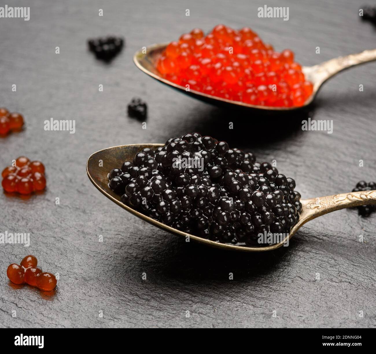 grainy caviar of paddlefish fish and red chum salmon caviar in a spoon, black background, close up Stock Photo