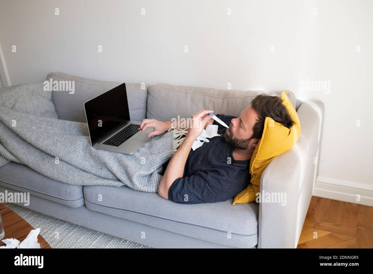 Man on sofa checking temperature Stock Photo