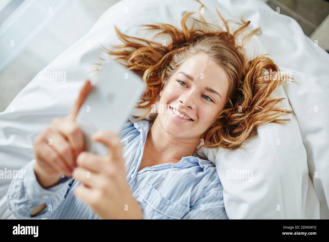 Woman using cell phone in bed Stock Photo