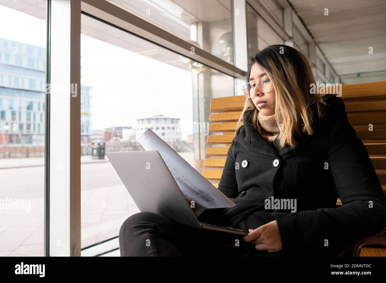 Woman at train station using laptop Stock Photo