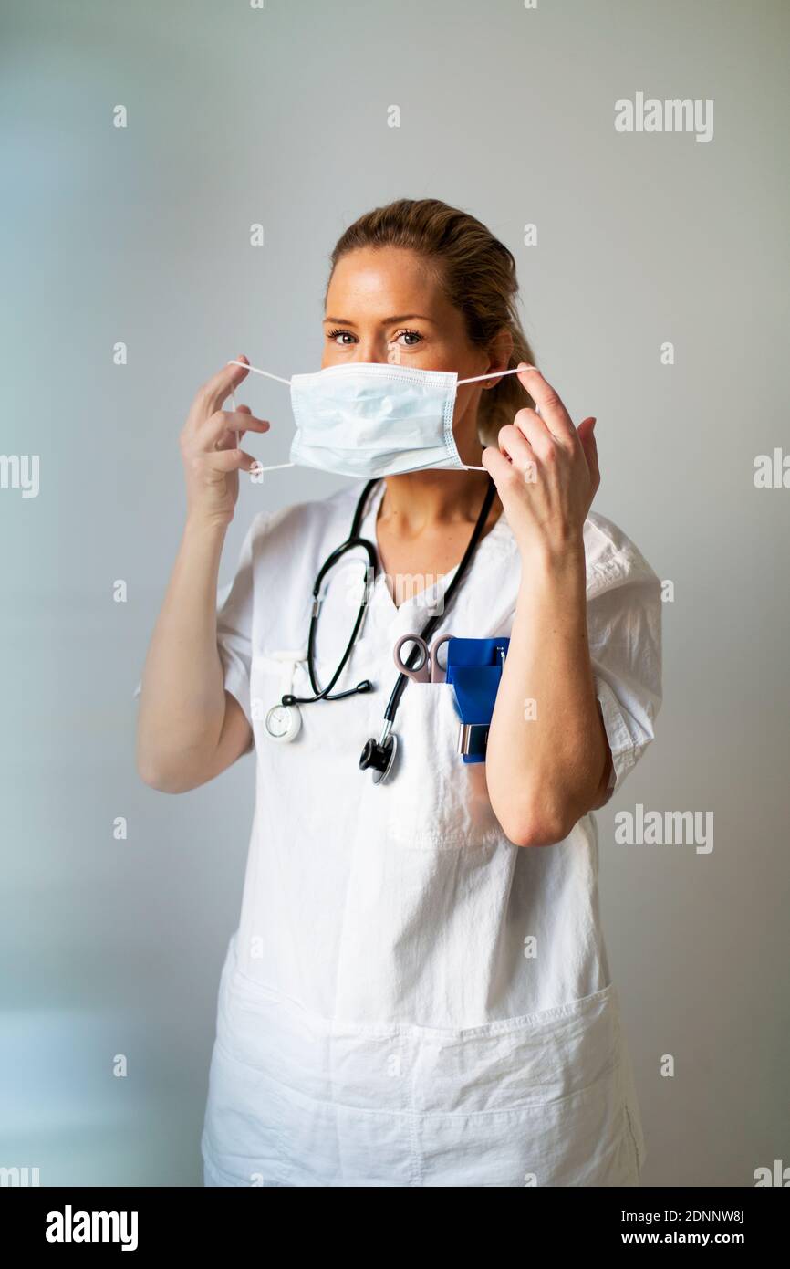 Female doctor putting protective face mask on Stock Photo