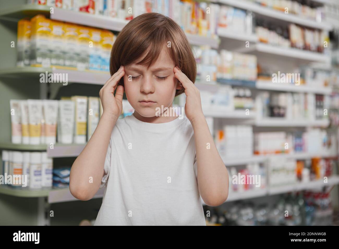 Close up of a little cute boy rubbing his temples, having headache, standing  at the drugstore, copy space. Adorable little boy having migraine, touchi  Stock Photo - Alamy