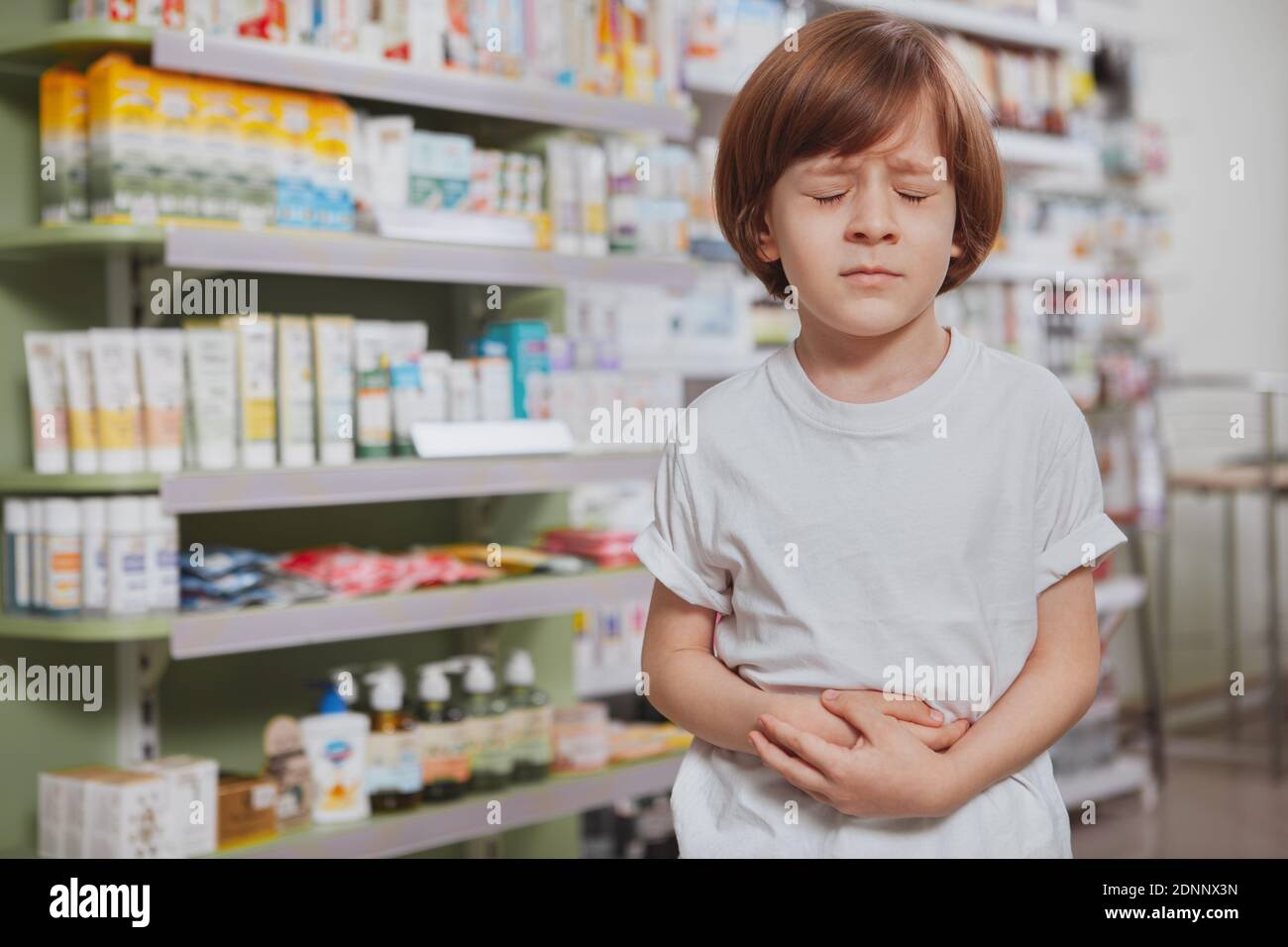 Little boy having terrible stomach ache, holding his belly with eyes