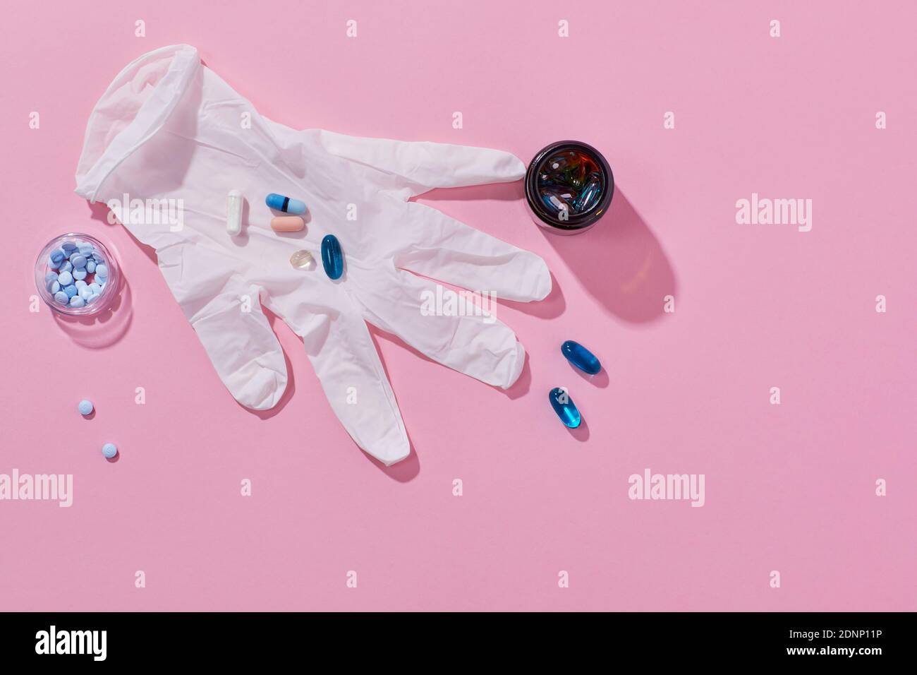 Pills on surgical glove on pink background Stock Photo