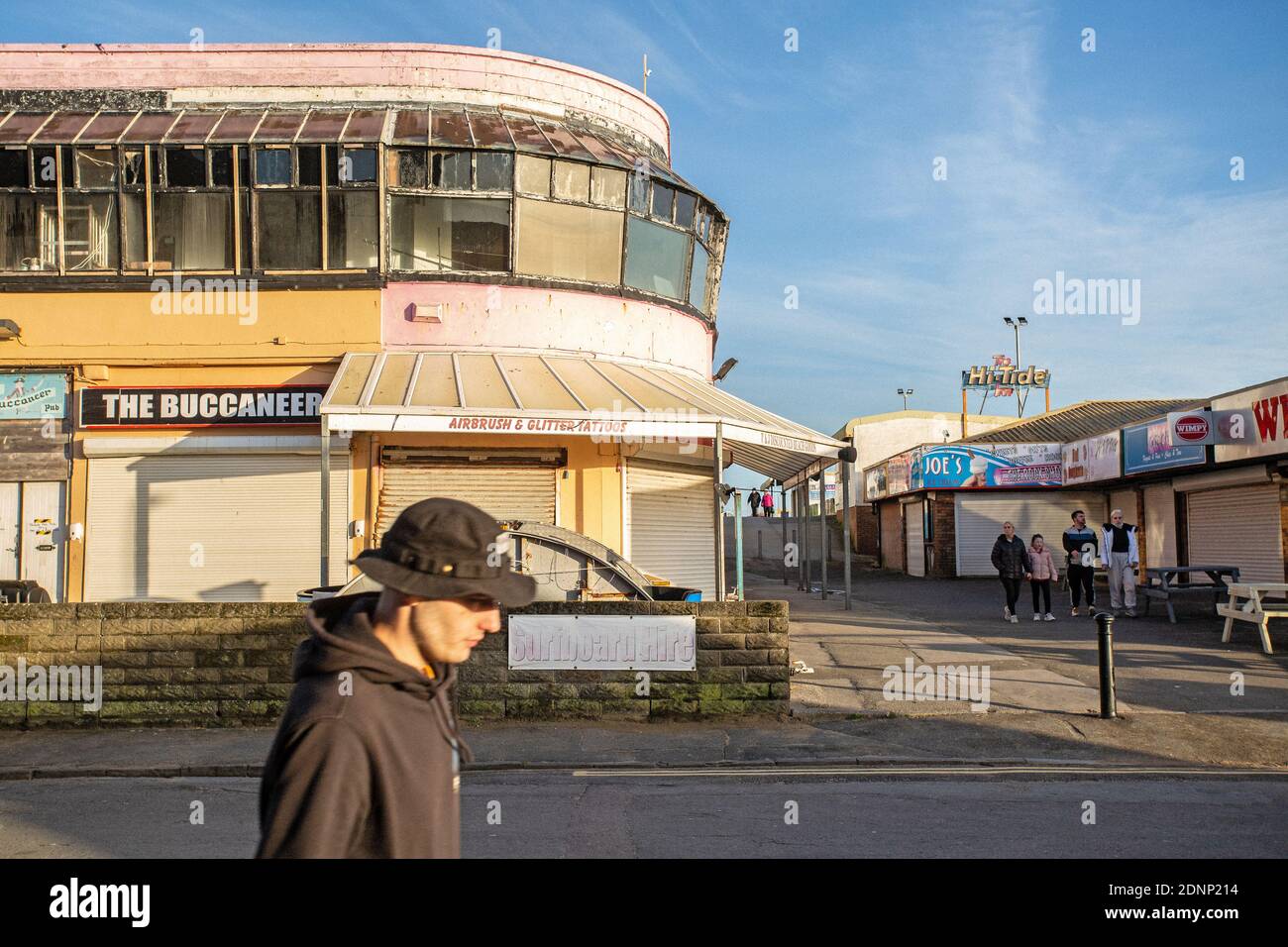 GREAT BRITAIN / Wales /Coney Beach Porthcawl / People passing the arcades and amusement park on the seafront where shops and stalls are closed . Stock Photo